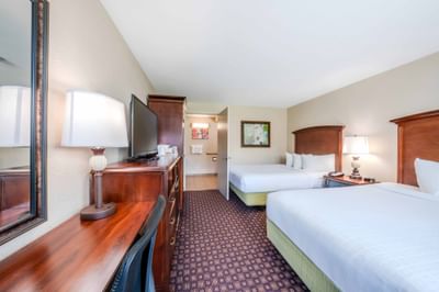 Double double guestroom with wood furniture, flat-screen TV, and patterned carpet at Rosen Inn International