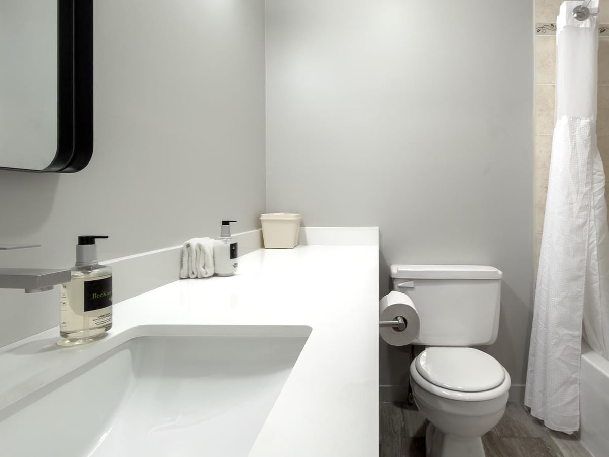 Bathroom with white sink, toilet, and tub at Coast Dawson Creek Hotel.