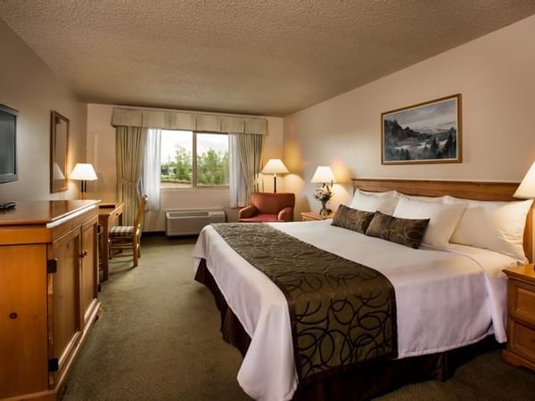Bed and sofa chair in hotel room with window