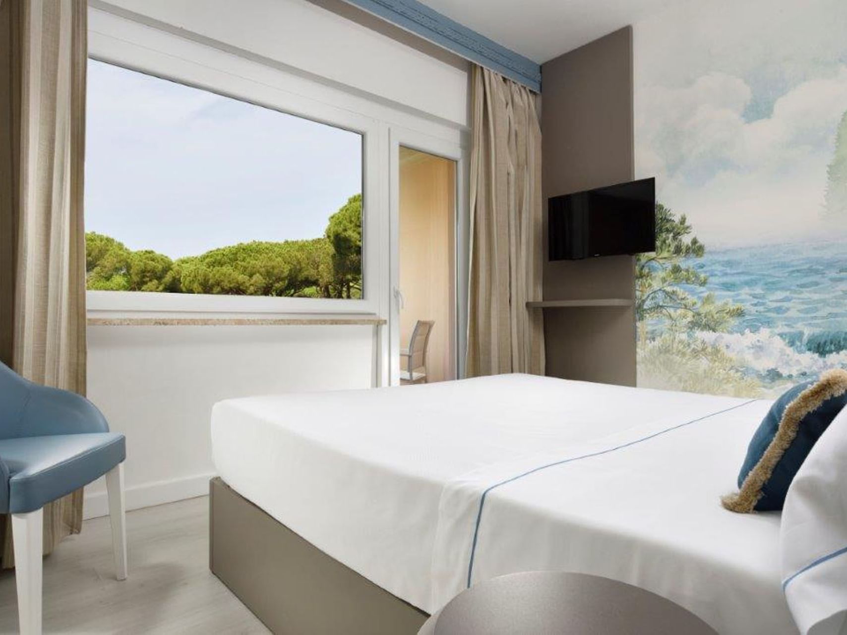 Bed & TV with a lake wallpaper in Deluxe Double Room Sea View at Golf Hotel Punta Ala