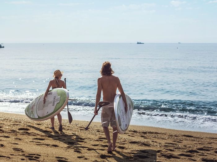 A couple surfing in a beach near Marbella Club Hotel