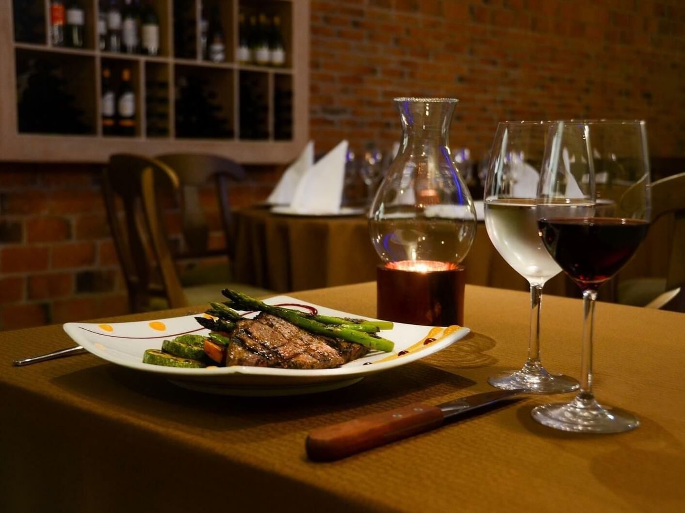 Delicious steak with asparagus and wine set on a table in a dimly lit restaurant at Fiesta Americana