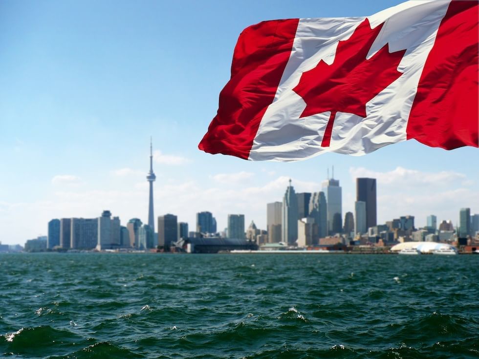 canadian flag flying majestically in the wind with the toronto hotel skyline in the background