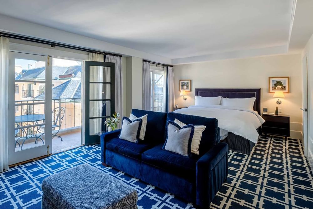 Room featuring a large bed with a blue sofa, and an inviting balcony at El Prado Hotel