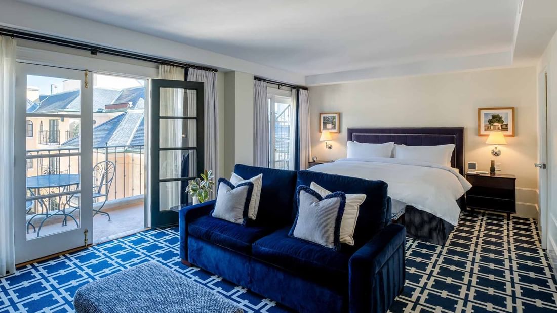 Cozy seating area by the bed in Courtyard Grand Executive King Suite with geometric patterned carpet at El Prado Hotel