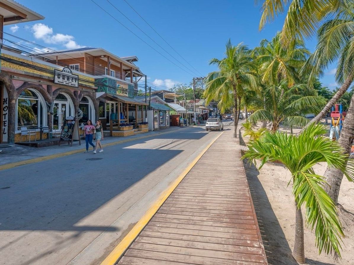 People walking on boardwalk by shops and palms enjoying things to do in Roatan at Barefoot Cay Resort & Marina