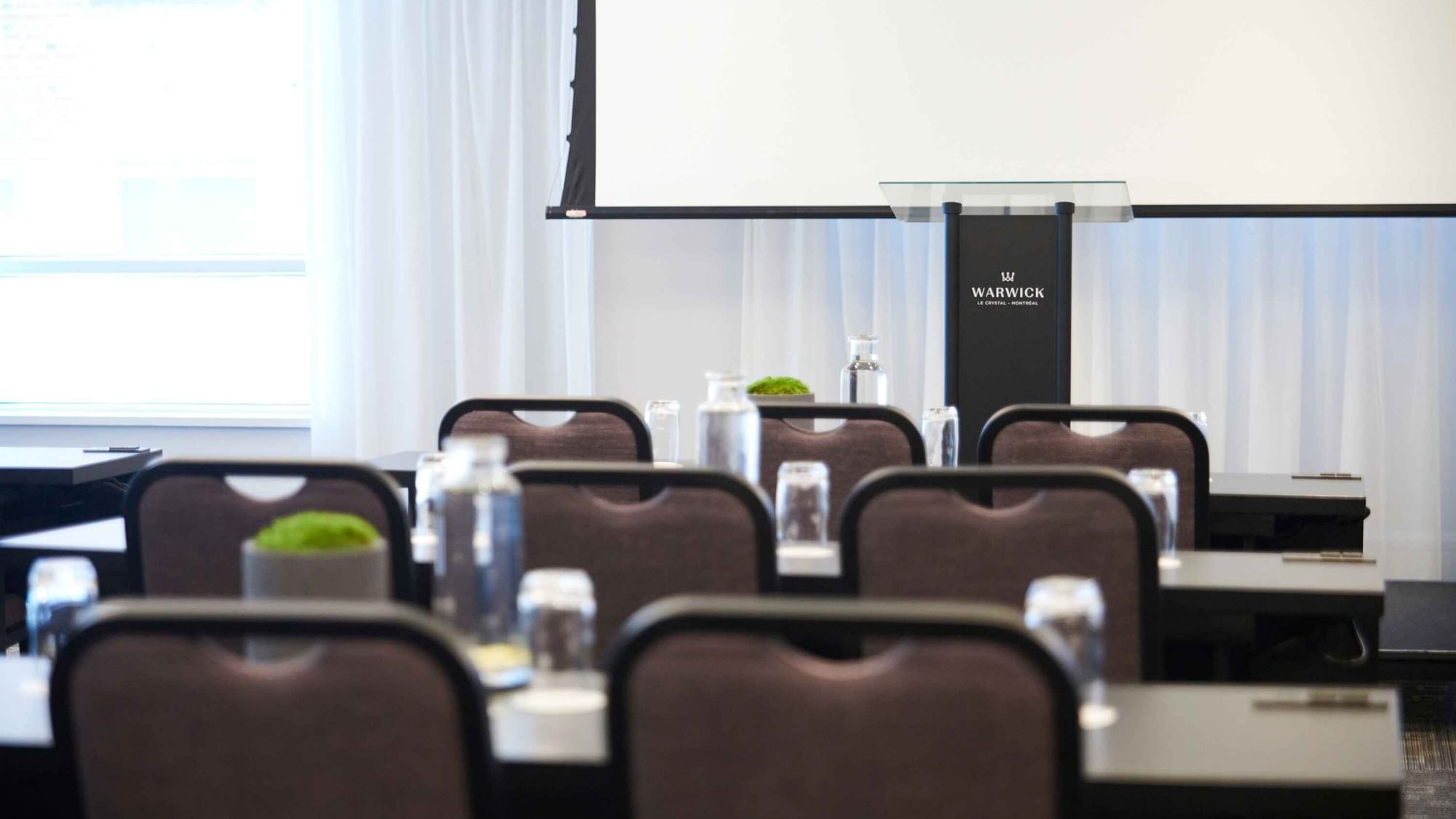 Classroom set-up with a projector screen in Salon Crescent at Warwick Hotels and Resorts