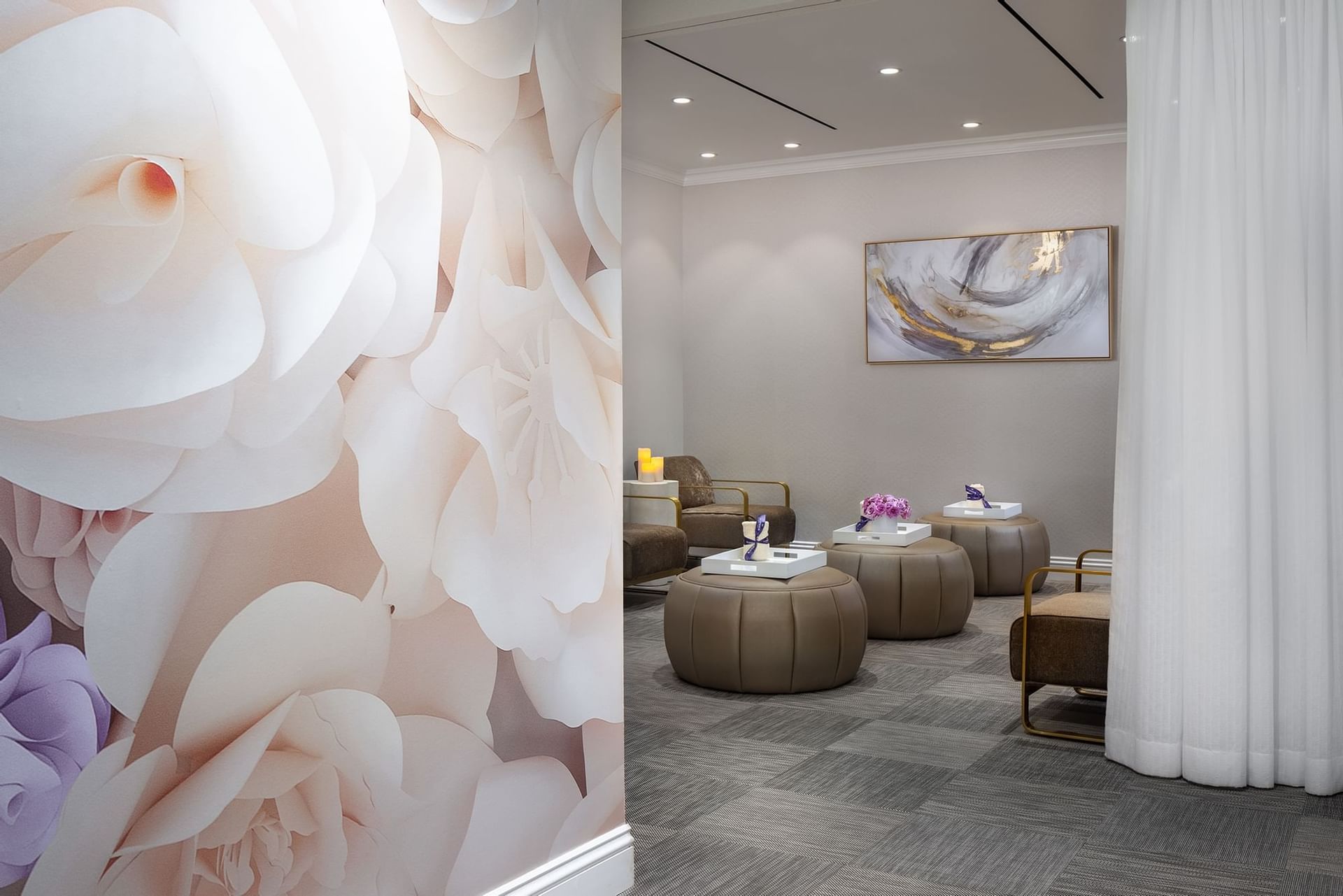 Plush ottomans by gold-framed chairs under an abstract painting in the spa at Warwick Melrose Dallas