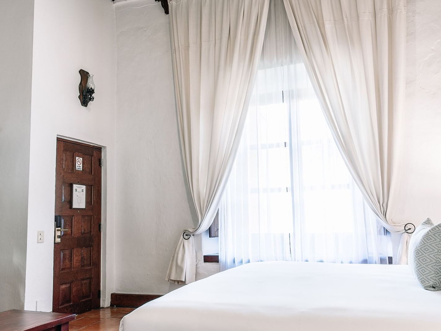 Bright, airy bedroom with white walls and curtains in the King Governor Suite at Quinta Real Oaxaca