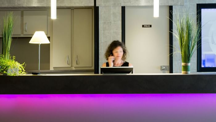 A receptionist at the reception desk in Hotel Les Caps