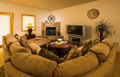 A cozy living room inside a suite at The Stanley Hotel featuring a large sectional sofa surrounding a fireplace