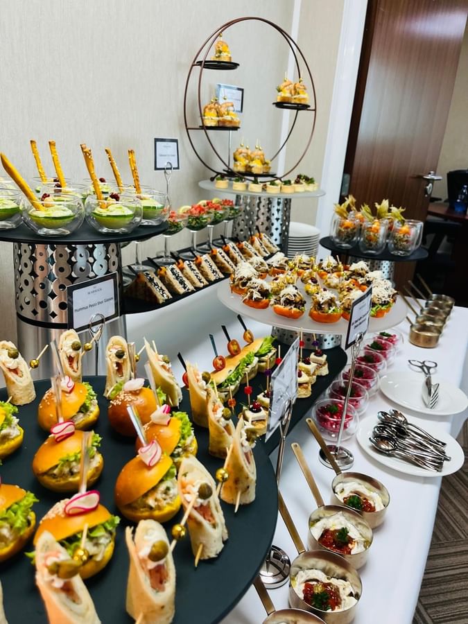 A variety of appetizers and finger foods displayed on a buffet table at Warwick Doha.