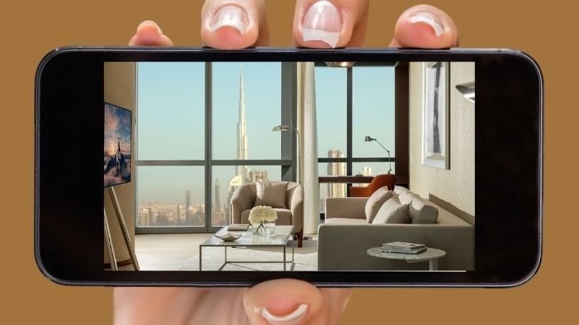 Hand with a phone showing the TV lounge area in a room at Paramount Hotel Midtown