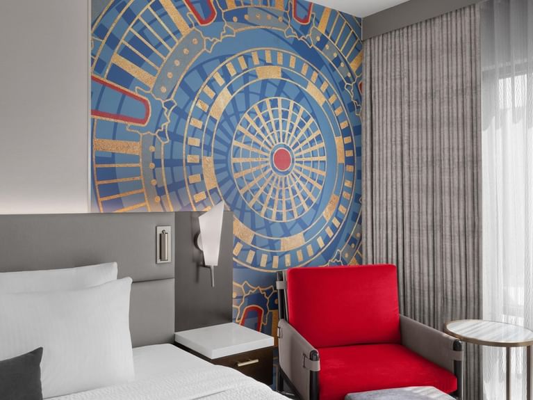 Boutique King room with an art work on the wall, a cozy red chair and a comfy bed at Hotel 43 Boise