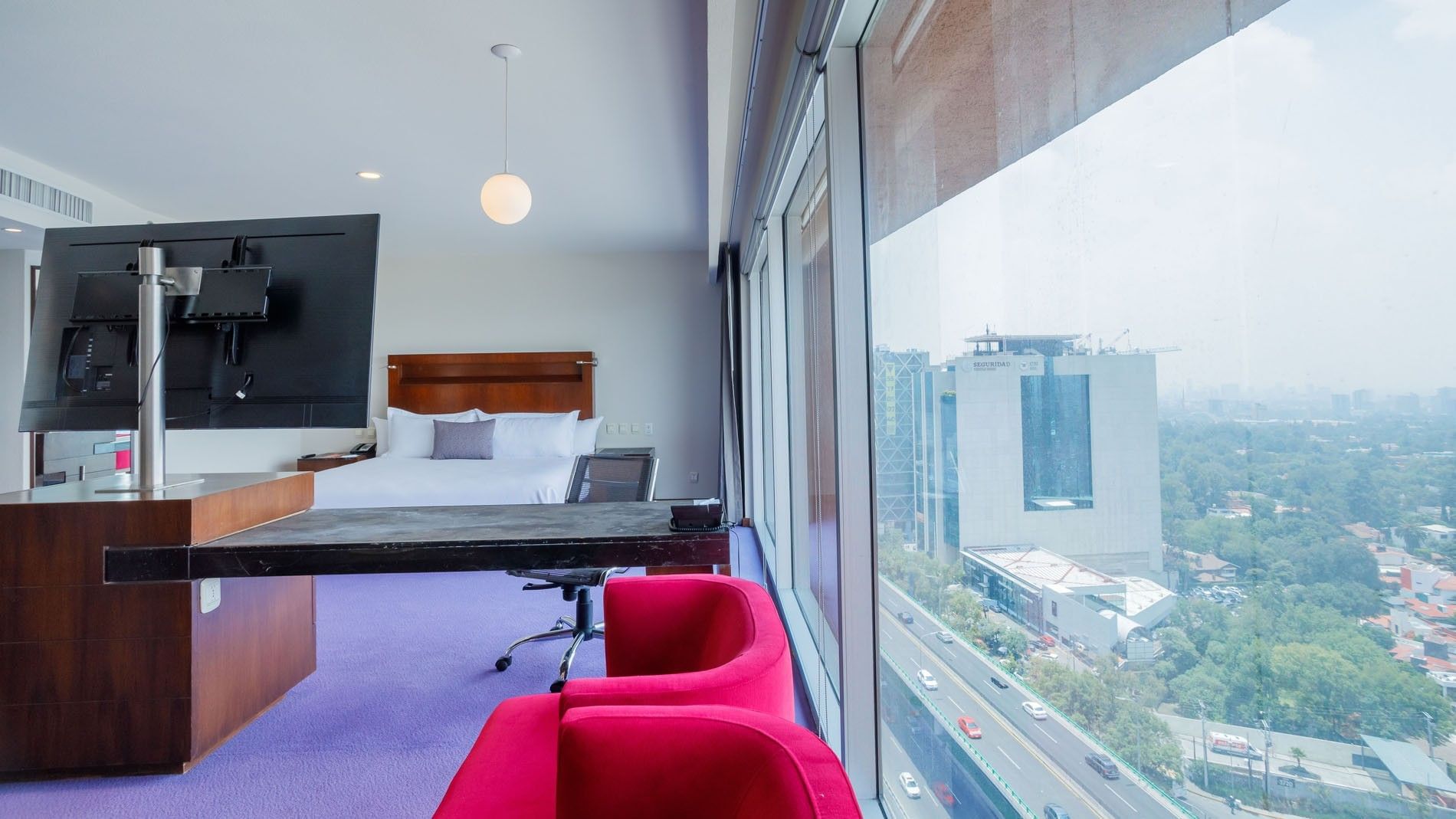 King Master Suite at Camino Real Pedregal Mexico, with red chairs by a window overlooking a busy city highway