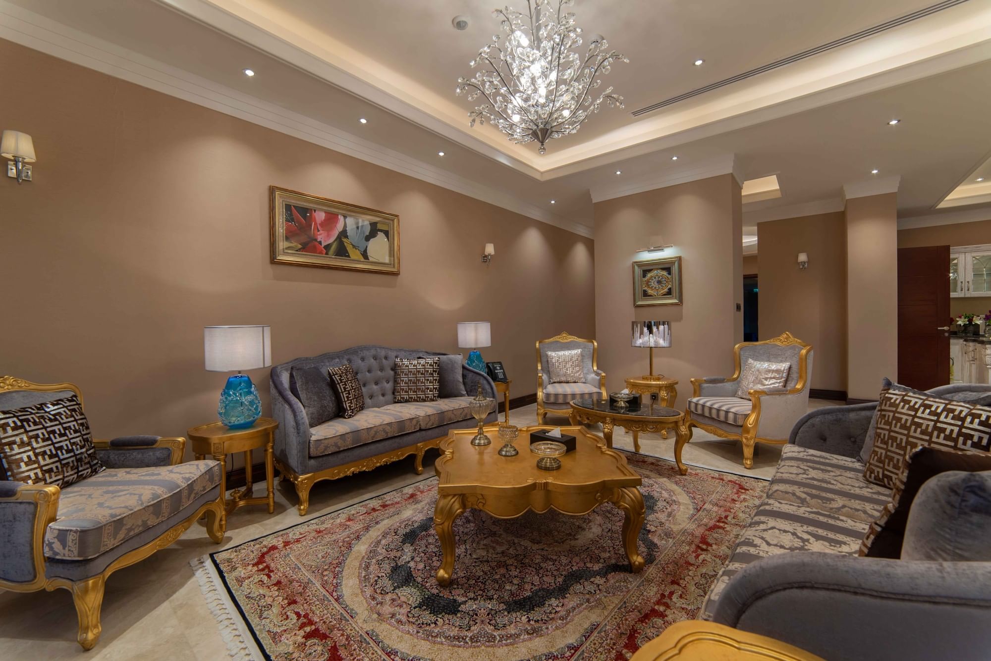 Tufted gray sofas by gold-carved coffee tables on a traditional Persian rug in Penthouse Villa at Warwick Al Khobar