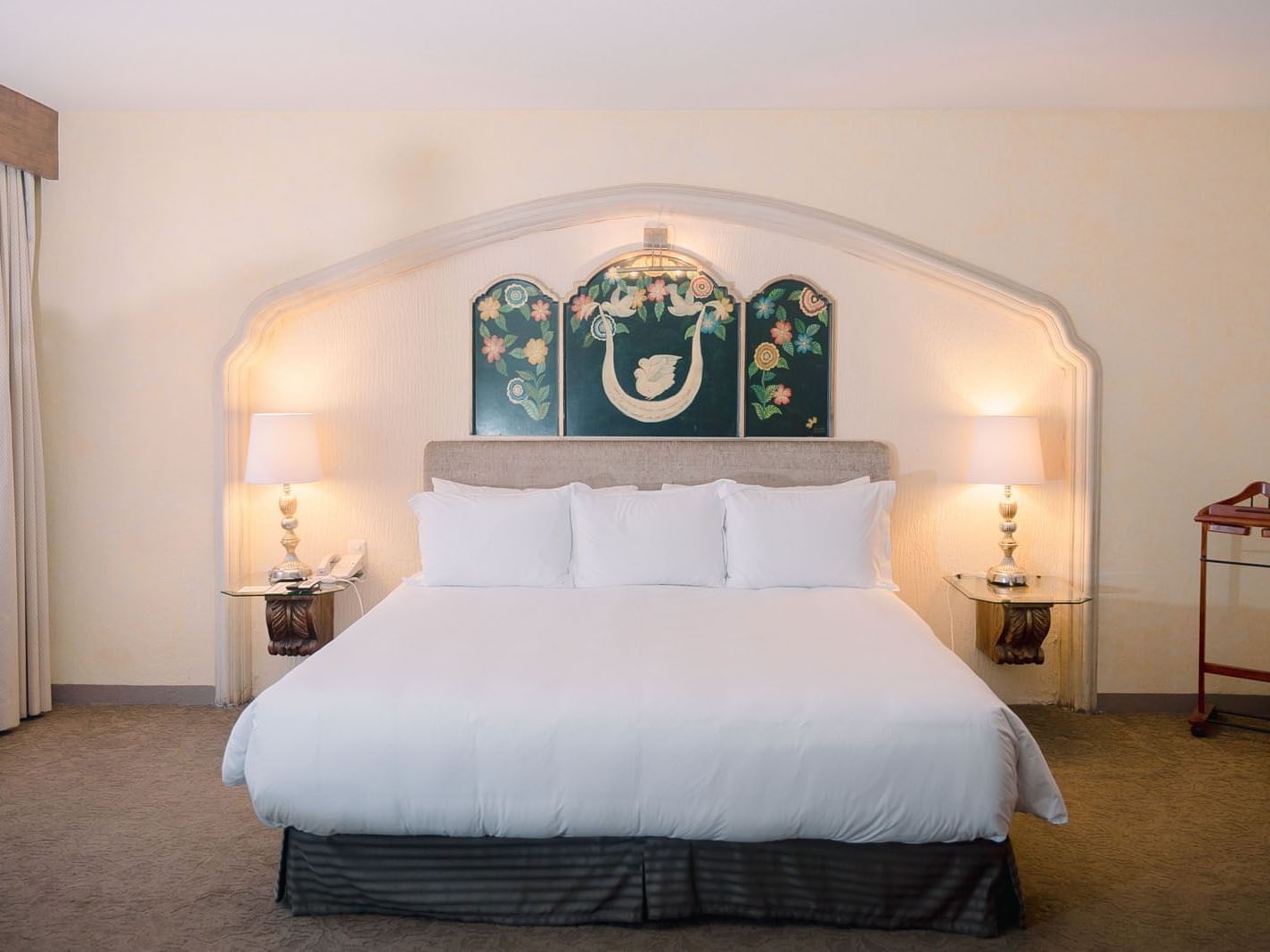King bed with white linens, side tables with lamps, and decorative wall art in King Grand Class at Quinta Real Zacatecas