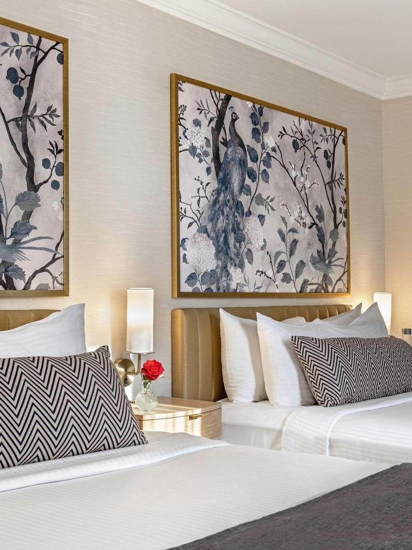 Bed with a side table under hanging pattern wall art in Two queen beds at Warwick Allerton Chicago