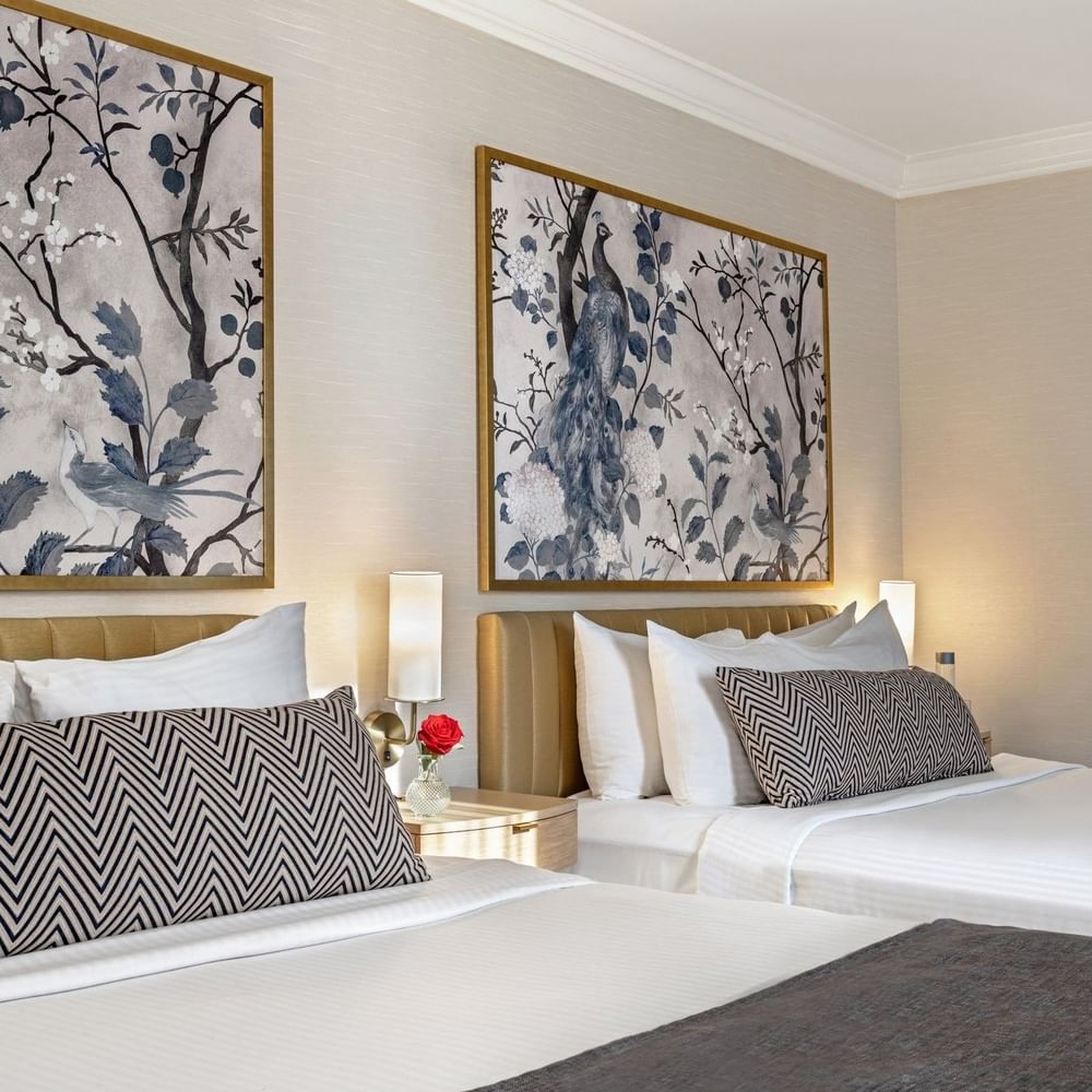 Two queen beds with floral wall art and bedside lamps at Warwick Allerton - Chicago.