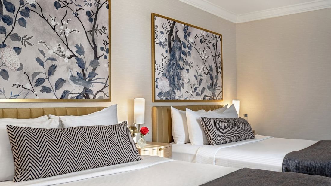 Bed with a side table under hanging pattern wall art in Two queen beds at Warwick Allerton Chicago
