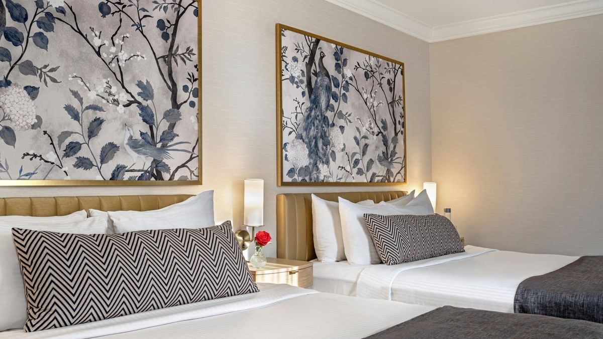 Two queen beds with floral wall art and bedside lamps at Warwick Allerton - Chicago.