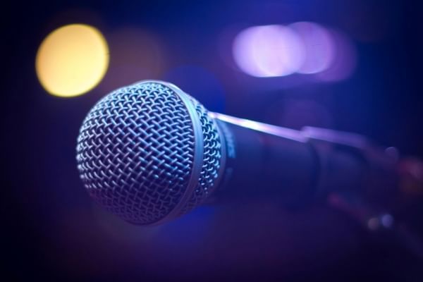 A closeup of a microphone in a blue lit space. 