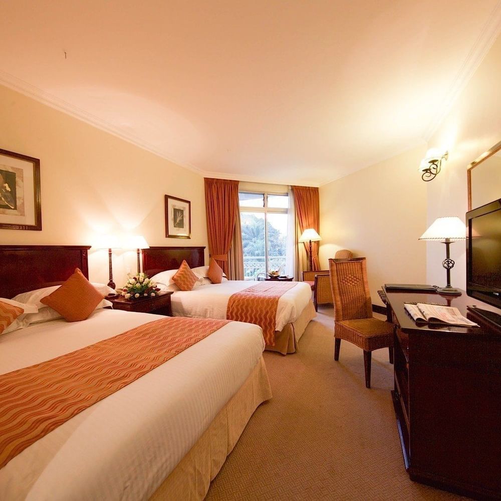 Family Room with two beds, desk, and TV at Lake Kivu Serena Hotel in Gisenyi.