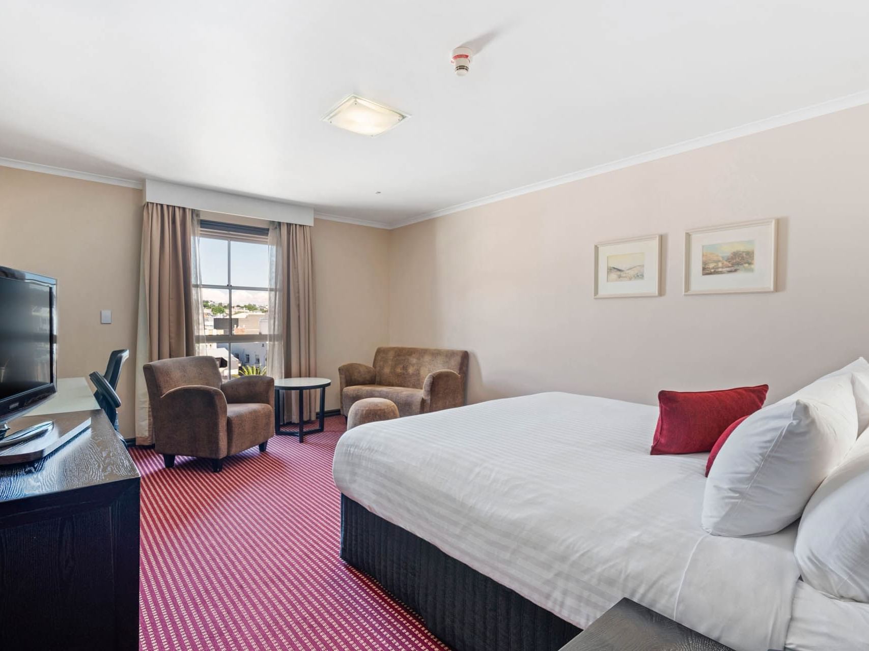 Large bed with sofas and work area in Superior King Room at Hotel Grand Chancellor Launceston