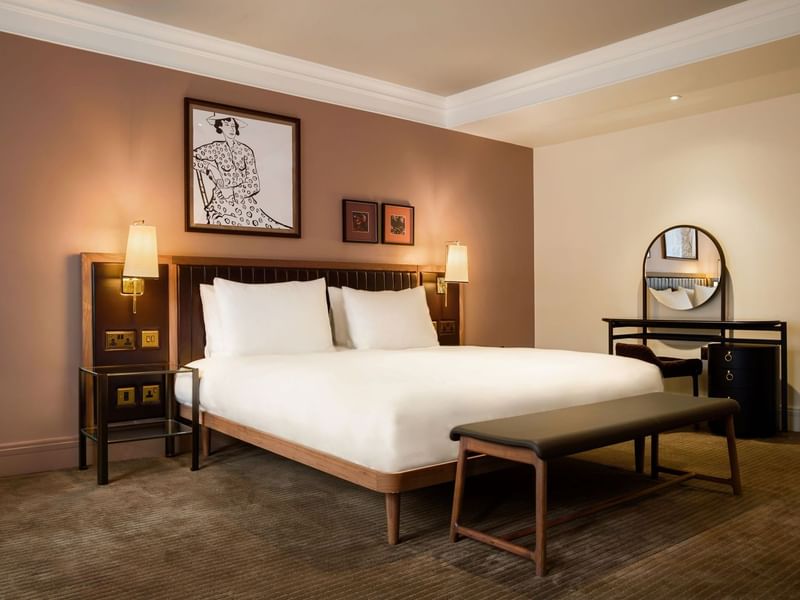Collection Superior Room with two white pillows, a large king bed, and a bench at The May Fair Hotel, London.