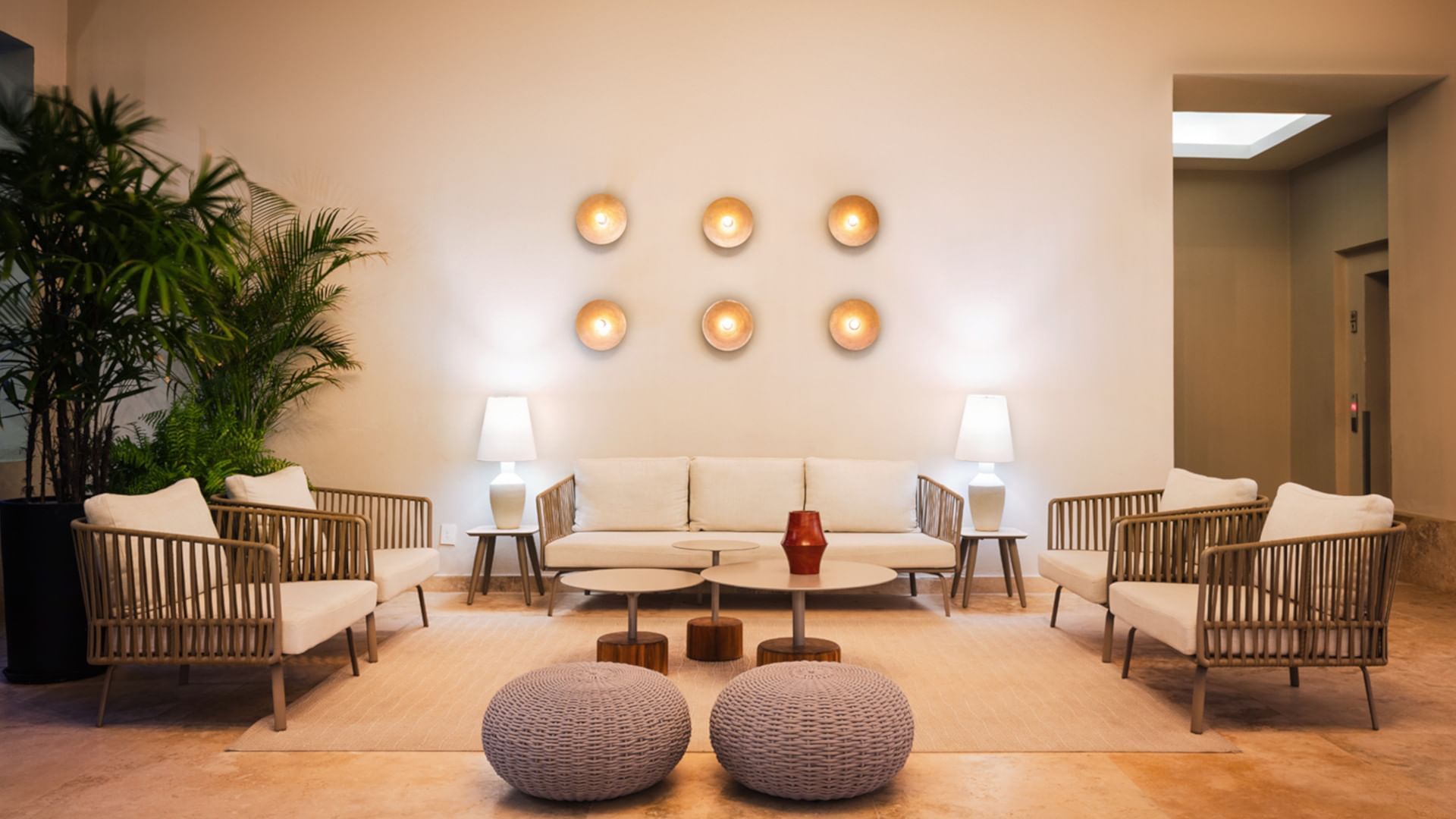 Minimalist lounge with white sofas, wicker chairs, and orb wall lighting at Camino Real Acapulco Diamante