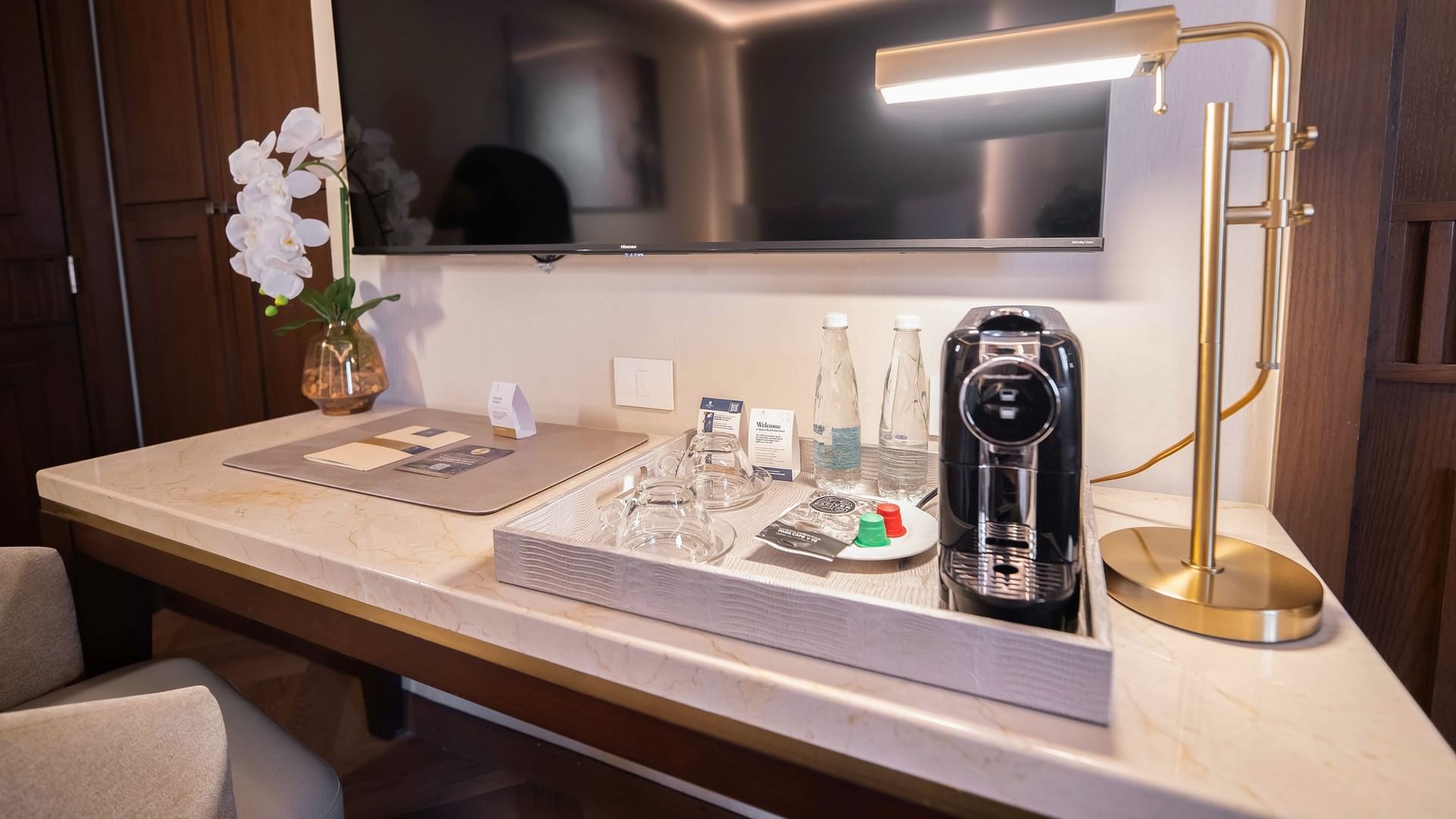 Escritorio con televisor, lámpara, café, y detalles de bienvenida en habitación New Class 2 Camas Dobles at Quinta Real Puebla en Heroica Puebla de Zaragoza