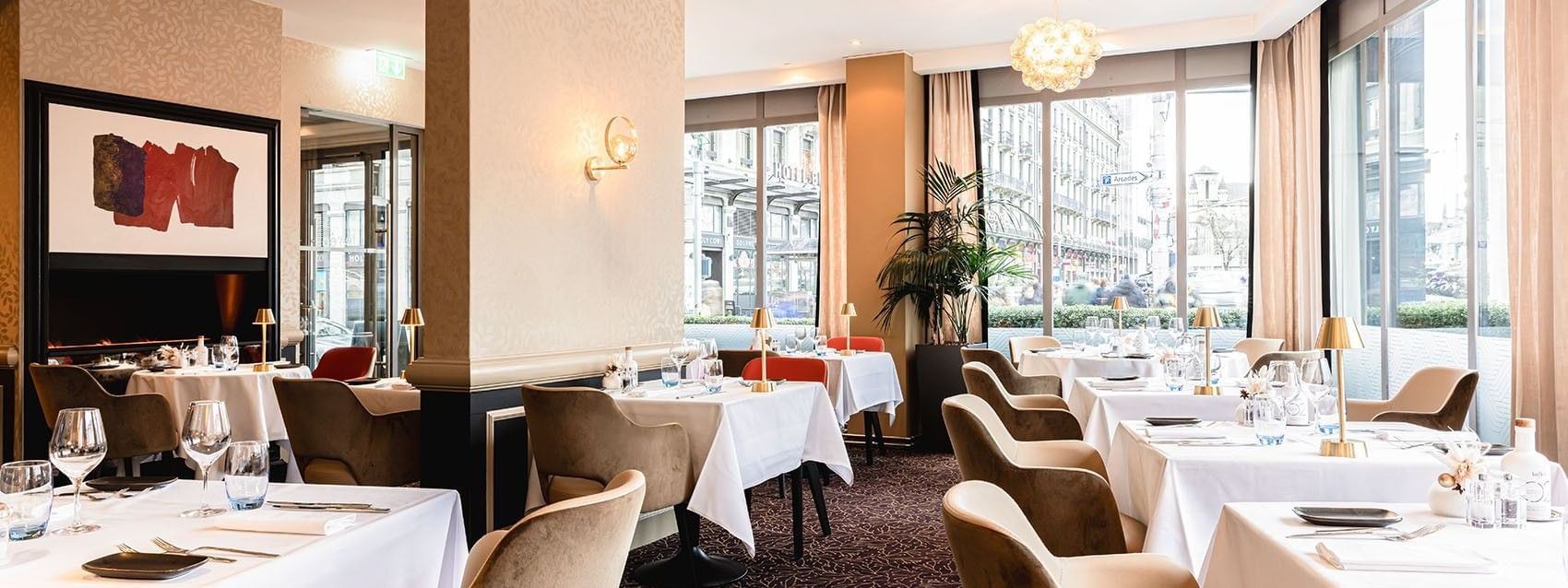 Plush armchairs surrounding white linen tables by bright city windows in Téséo at Warwick Geneva