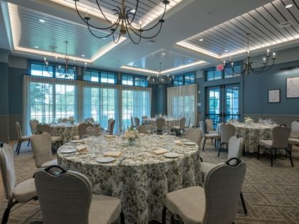 Elegant event space with round tables, floral linens, upholstered chairs, and chandeliers at Camp Creek Inn, Inlet Beach