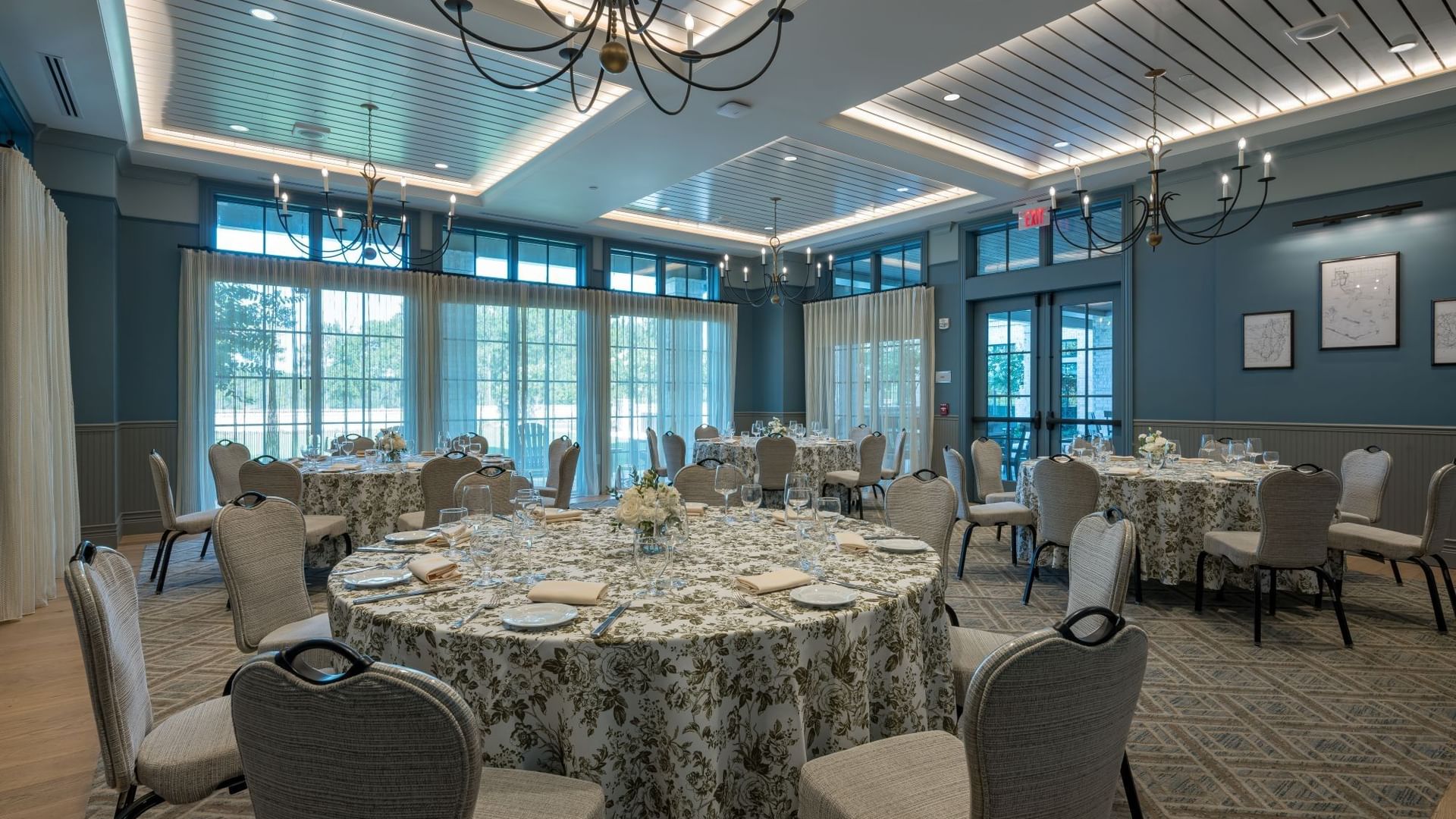 Elegant event space with round tables, floral linens, upholstered chairs, and chandeliers at Camp Creek Inn, Inlet Beach