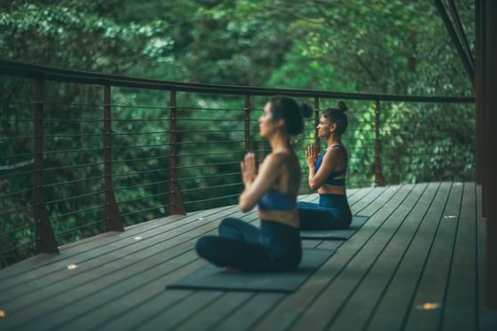 Two women doing yoga on a wooden deck in Wellness Center at El Silencio Lodge & Spa