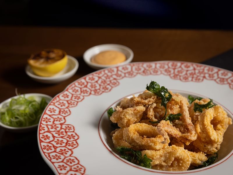 Crispy fried calamari with garnishes, served in a decorative bowl at El Prado Hotel