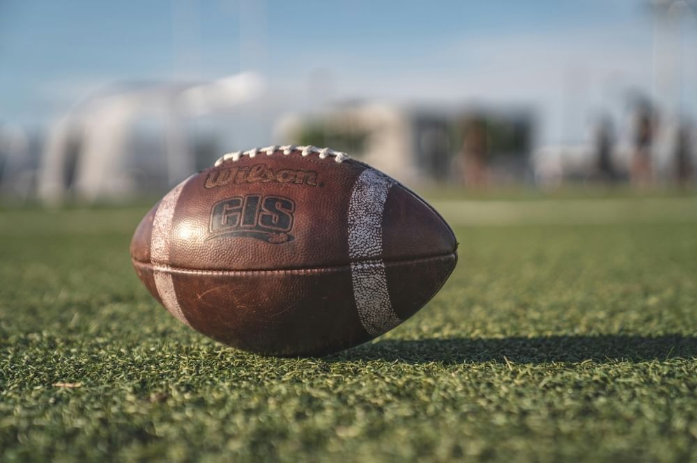 A close-up of a football sitting on green turf. 