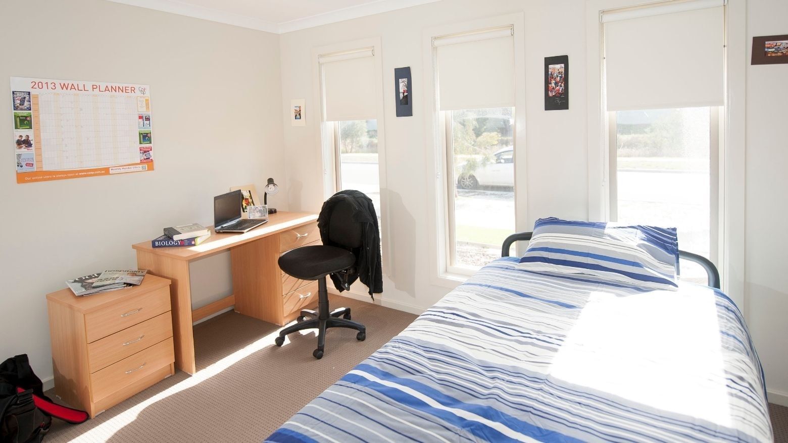 Neat student bedroom with bed, desk, chair, and open windows at La Trobe University Regional Housing – Shepparton.