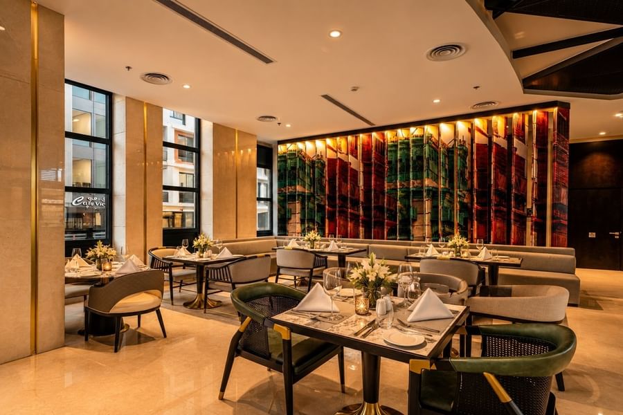 Roshen Restaurant seating with chairs around set dining tables beside a cityscape wall at Naviti by Warwick Jeddah