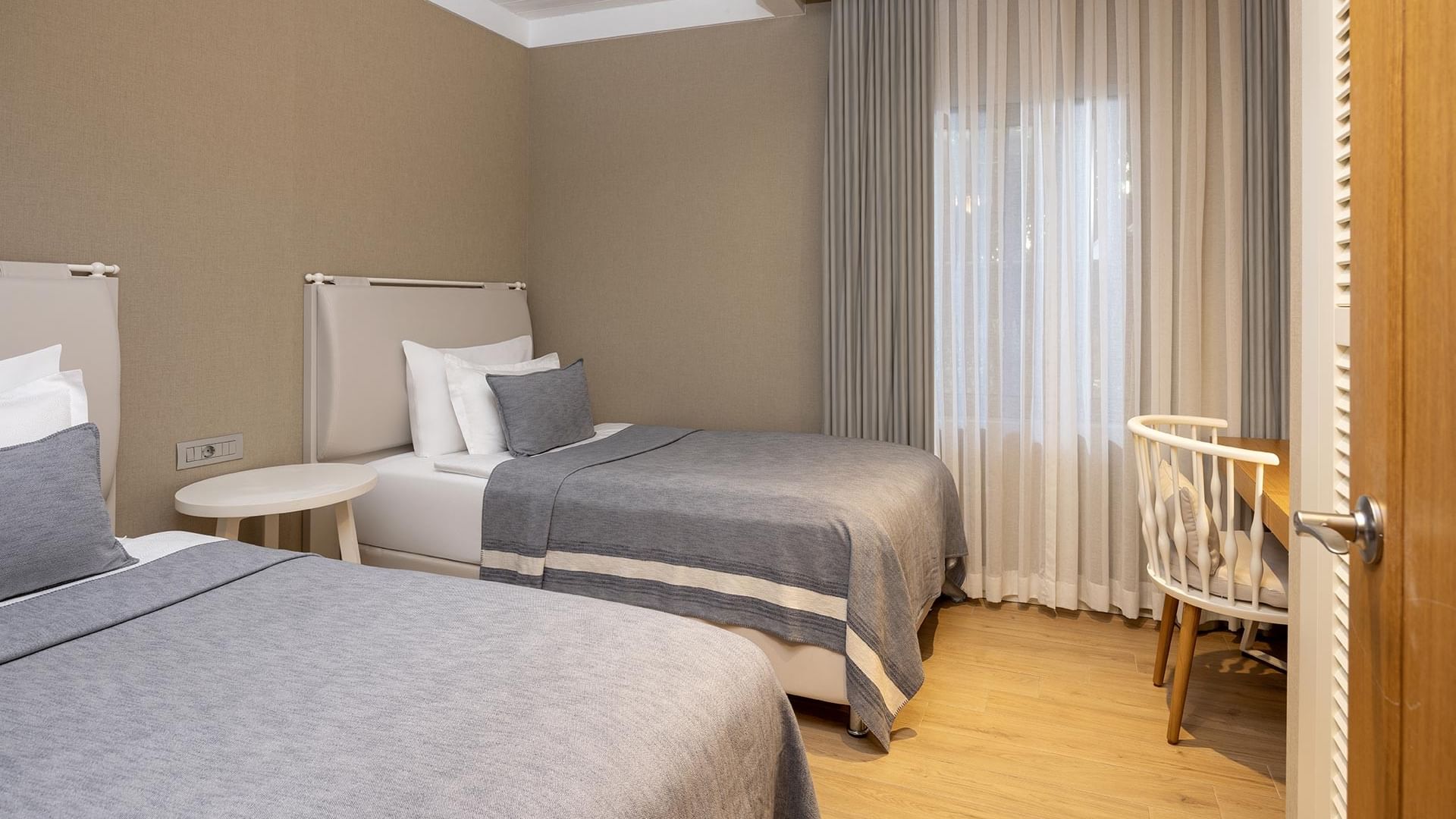 Спальня семейного люкса Swim-up в Titanic Luxury Collection Bodrum с двумя кроватями, рабочим столом и стулом