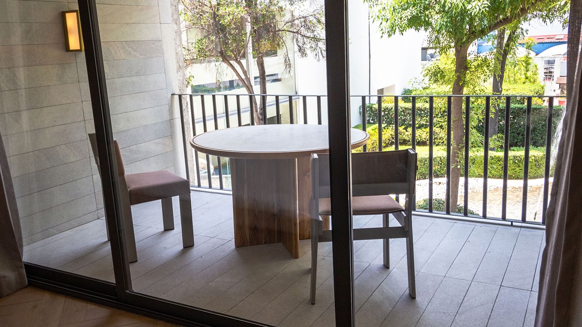 King Superior Viceroys Suite balcony with a table and chairs overlooking lush green trees at Camino Real Polanco Mexico
