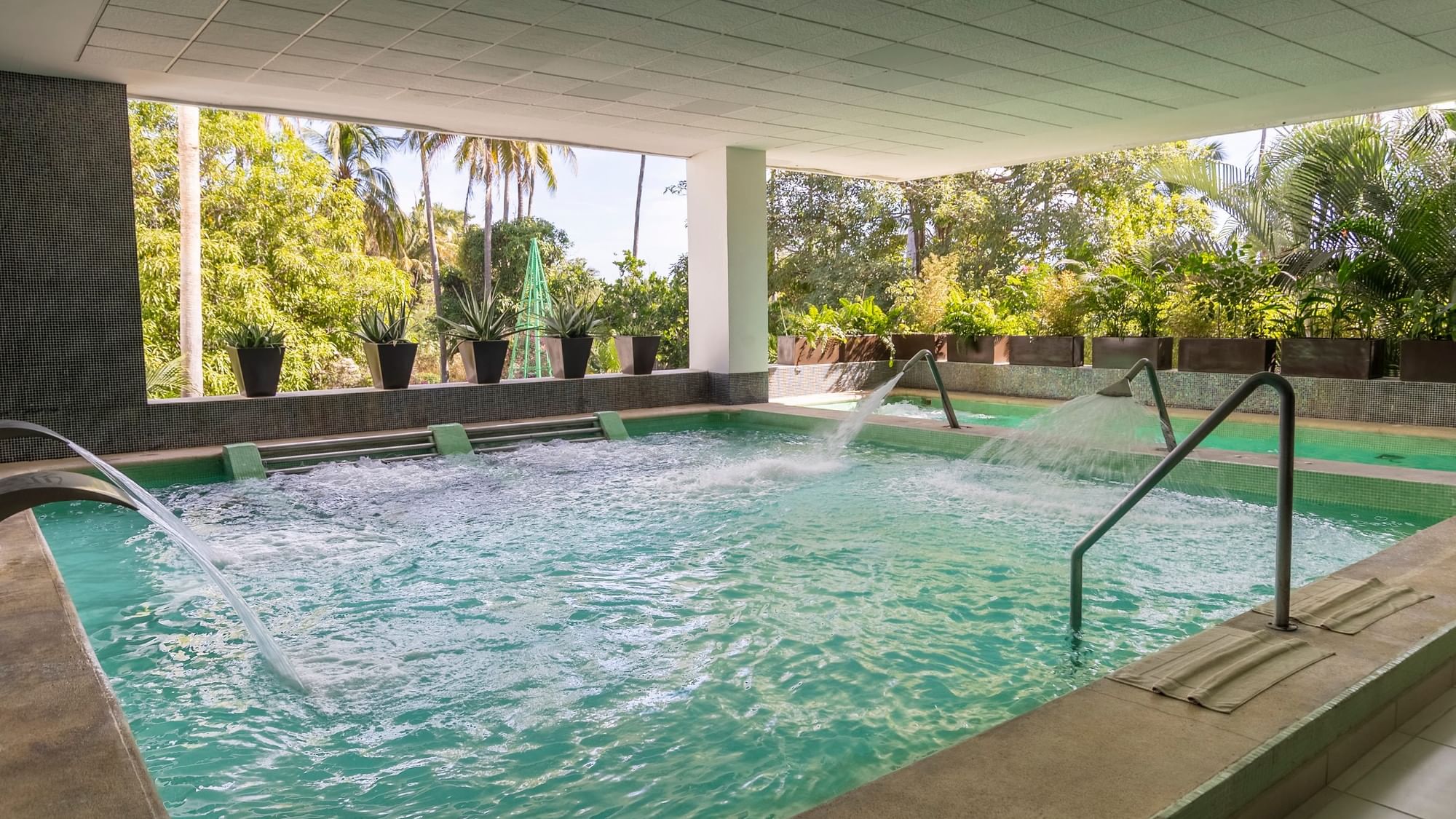 Piscina con chorros de agua y vegetación en el exterior del Fiesta Americana Riviera Nayarit Resort & Spa