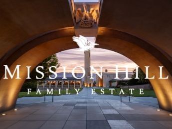 Arch entrance with Mission Hill Family Estate Winery sign in front of illuminated building.