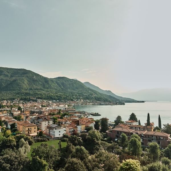 Coastal town with terracotta roofs by a calm lake under mountains, surrounding Falkensteiner Hotels & Residences