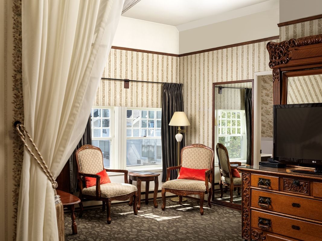 Living area with a table and chairs by the window & a TV in Victoria Room at Pendray Inn & Tea House