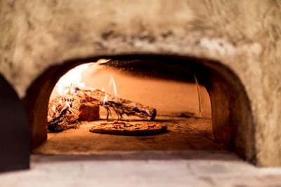 A pizza baking inside a wood-fired oven with flames at Villa Premiere Boutique Hotel & Romantic Getaway