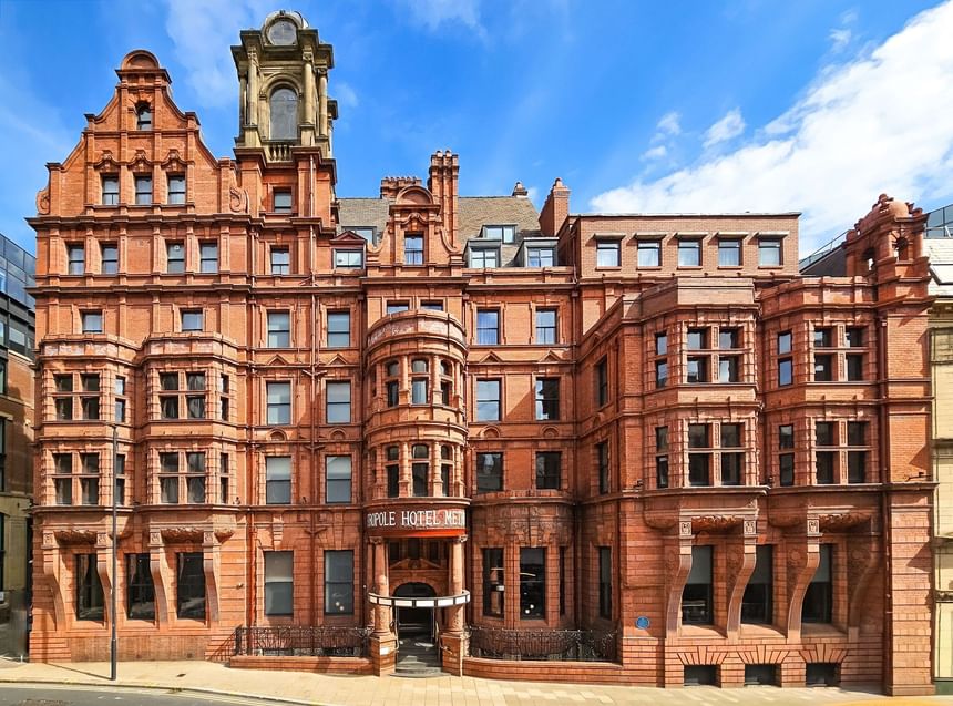 Magnificent exterior of The Met Hotel Leeds in England, showcasing red-brick Victorian architecture under a bright blue sky