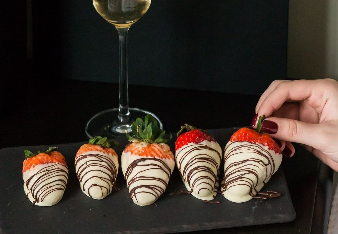 Chocolate dipped strawberry plate with a wine glass on the table at The May Fair Hotel