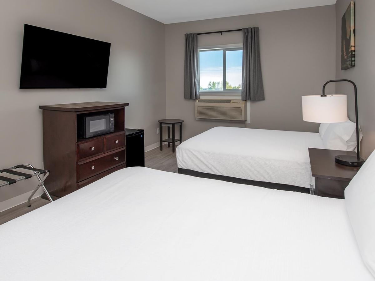 Two queen beds with nightstands and a TV in a room at Coast Innisfail Hotel.