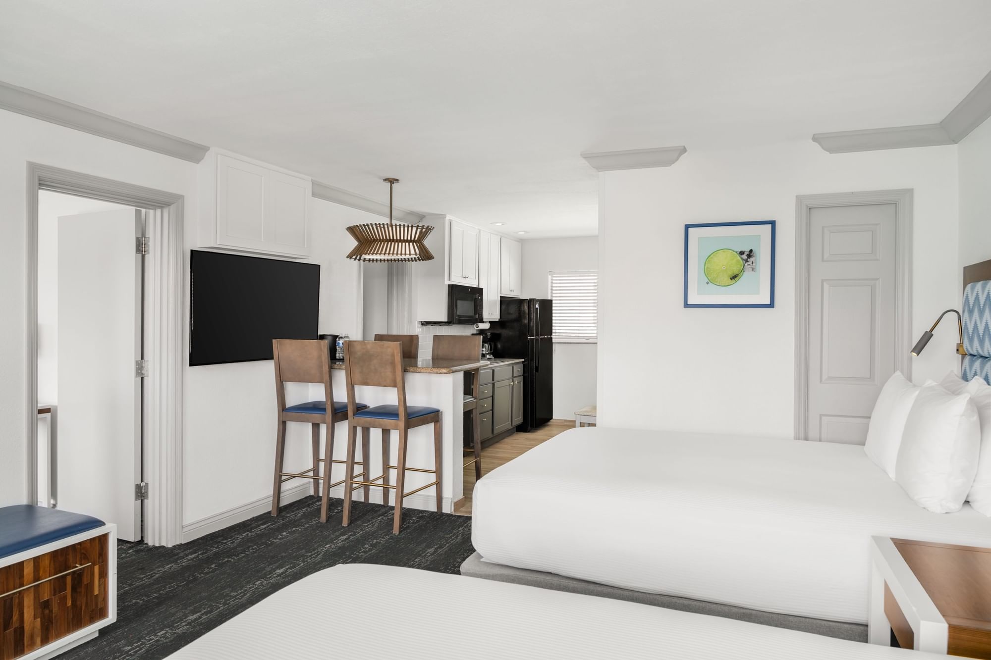 A wide view of a hotel suite with a kitchenette, a sofa bed, and a flat screen TV.